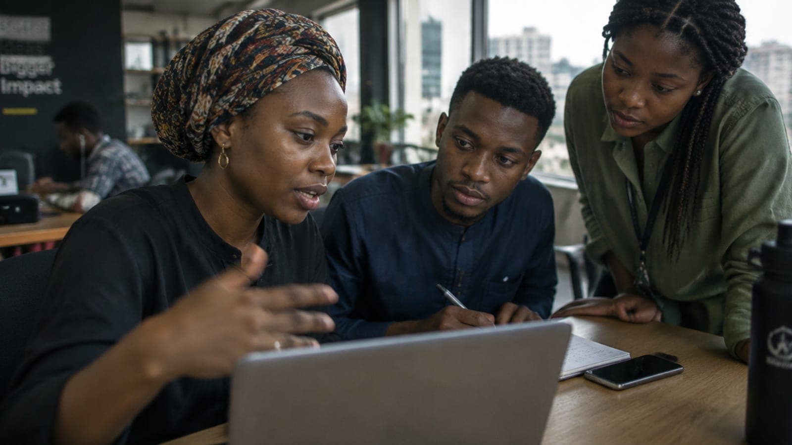 Three young Nigerian professionals working together around a laptop