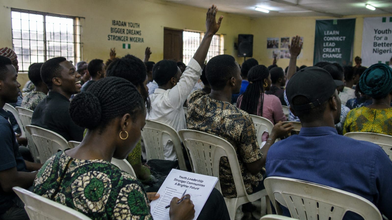 Young people at a Wissen-Haus community event, hands raised to ask questions